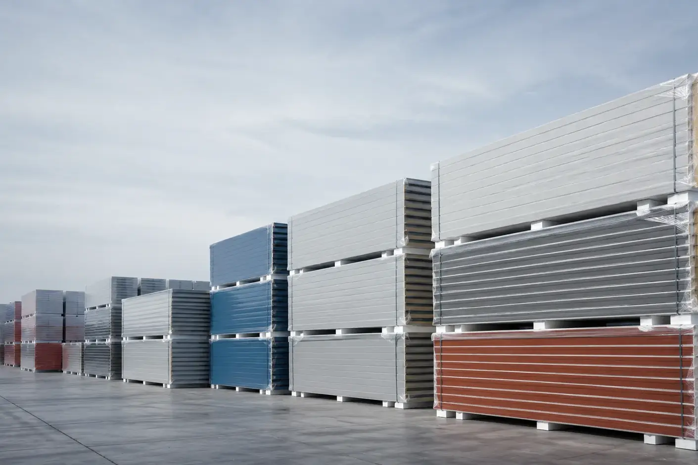 Stacked bundles of finished sandwich panels in a factory yard illustrating sandwich panel cost factors
